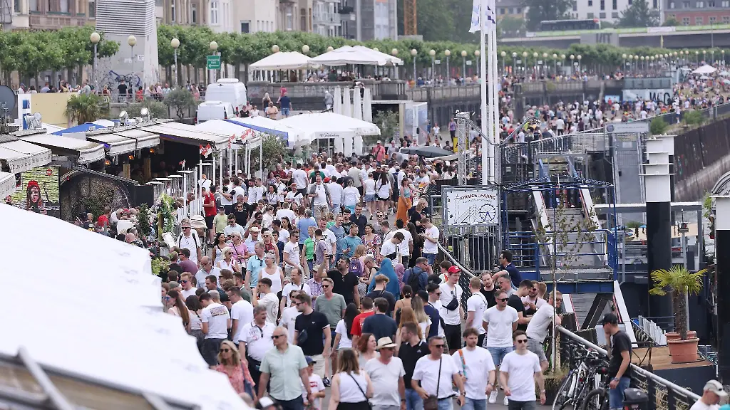Zahlreiche-Menschen-gehen-bei-sommerlichen-Temperaturen-ueber-die-Rheinuferpromenade-in-Duesseldorf