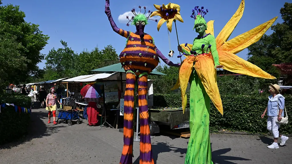 Stelzenlaeufer-in-bunten-Kostuemen-unterhalten-die-Gaeste-in-der-Dauerkleingartenanlage-Rehberge