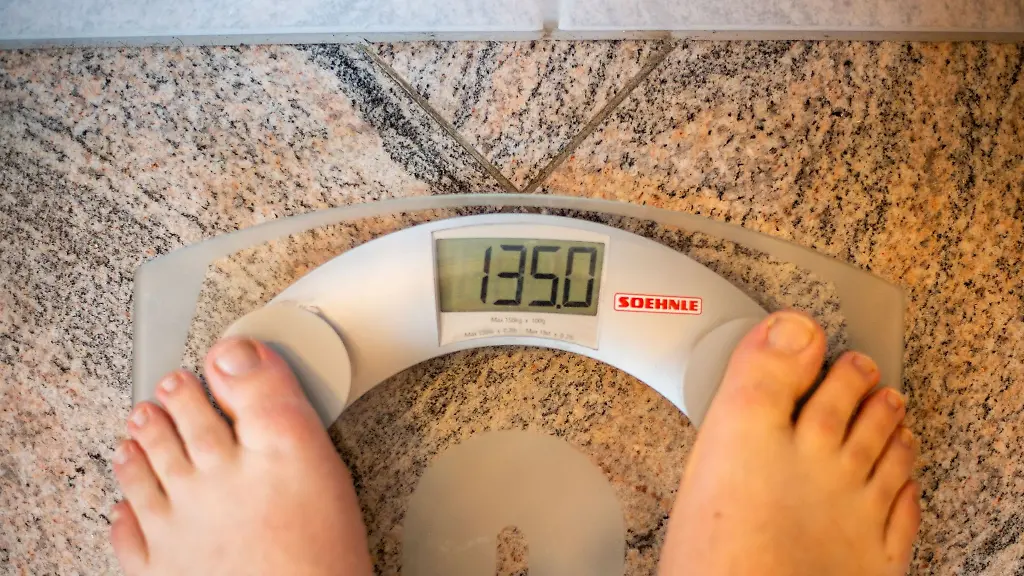 Ein-Mann-steht-auf-einer-Waage