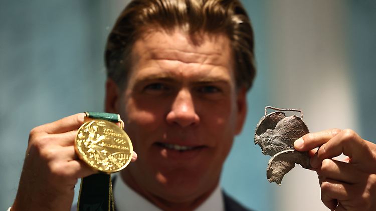 Der frühere Schwimmer Gary Hall Jr. zeigt seine neue und seine von dem Feuer zerstörte Olympia-Medaille.