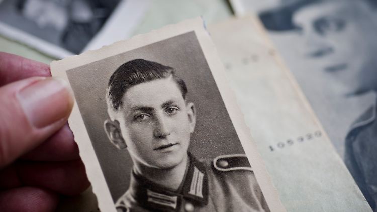 Ein Mitarbeiter des Deutschen Suchdienstes München zeigt ein Porträtbild eines vermissten deutschen Soldaten.