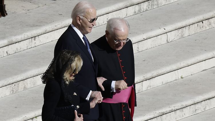Biden muss bei der Beerdigung von Papst Franziskus von seiner Frau und einem Geistlichen beim Herabsteigen einer Treppe gestützt werden. 