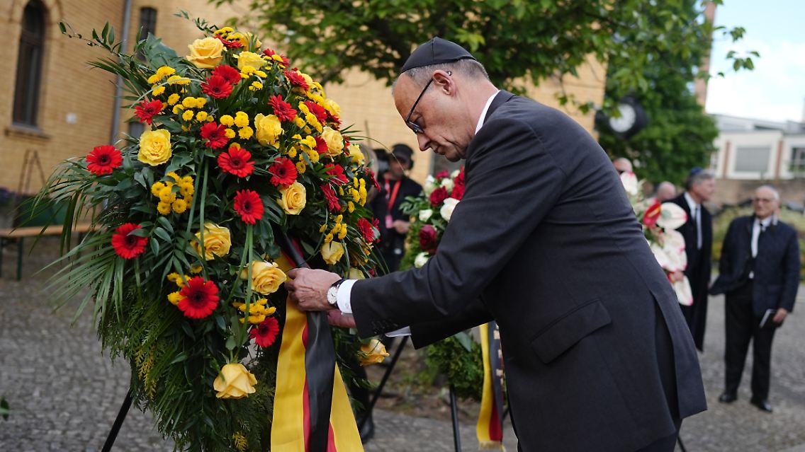 Friedrich Merz drapiert einen Kranz.