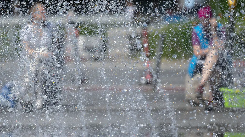 Zwei-Frauen-sitzen-in-der-Innenstadt-an-einem-Springbrunnen-in-der-Sonne