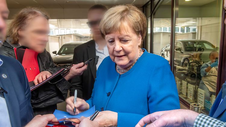 Umringt von Fans: Die ehemalige Kanzlerin verteilt in München Autogramme.