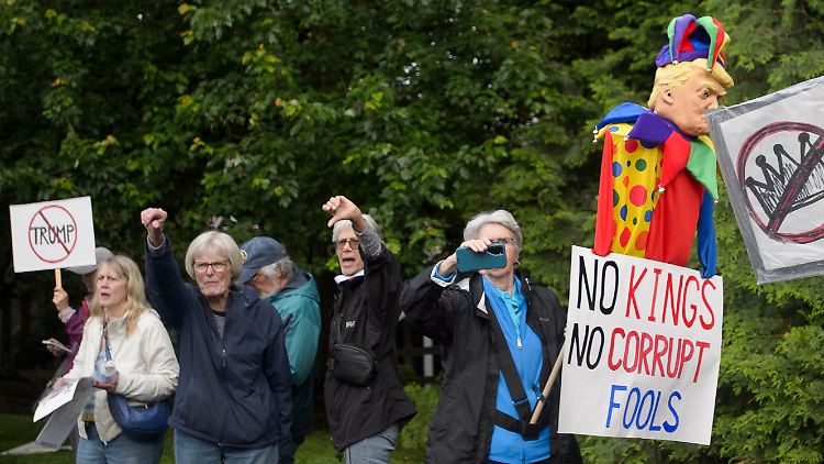 Etwa 100 Menschen protestieren vor dem Golfclub gegen Trump.