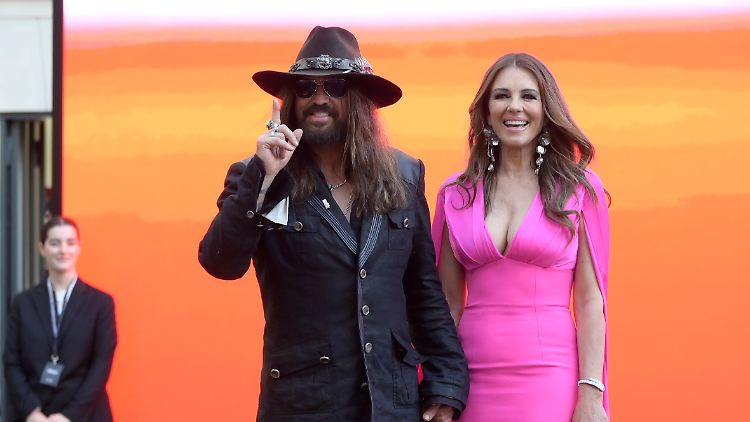 Gegensätze ziehen sich offenbar an - zumindest was die Outfits betrifft: Billy Ray Cyrus und Elizabeth Hurley.