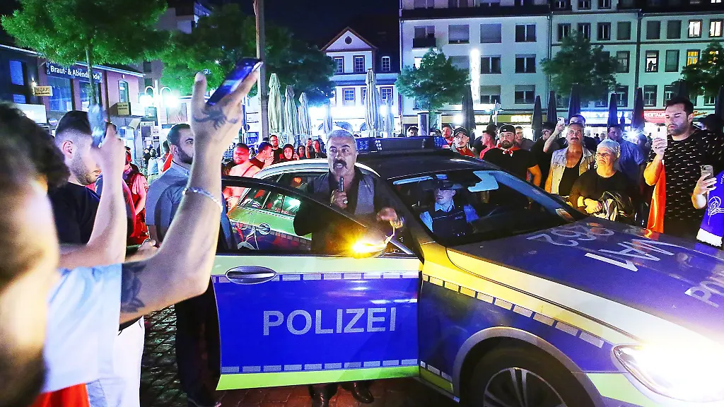 Die-Polizei-ist-in-der-Innenstadt-im-Einsatz-waehrend-Menschen-um-ein-Polizeiauto-stehen