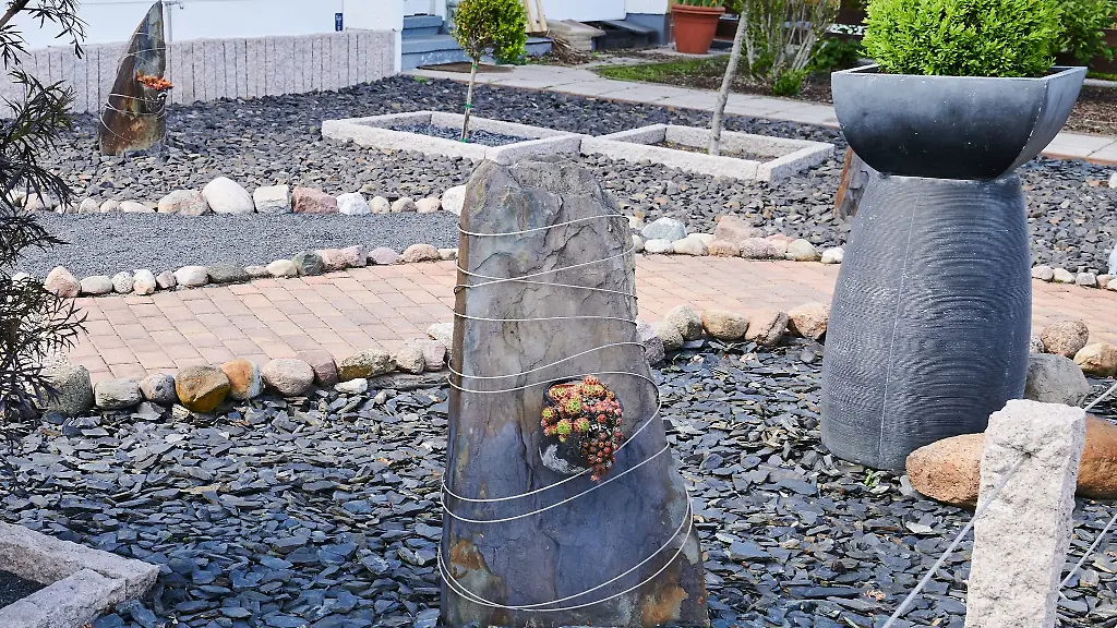 Groessere-und-kleinere-Steine-liegen-in-einem-Vorgarten