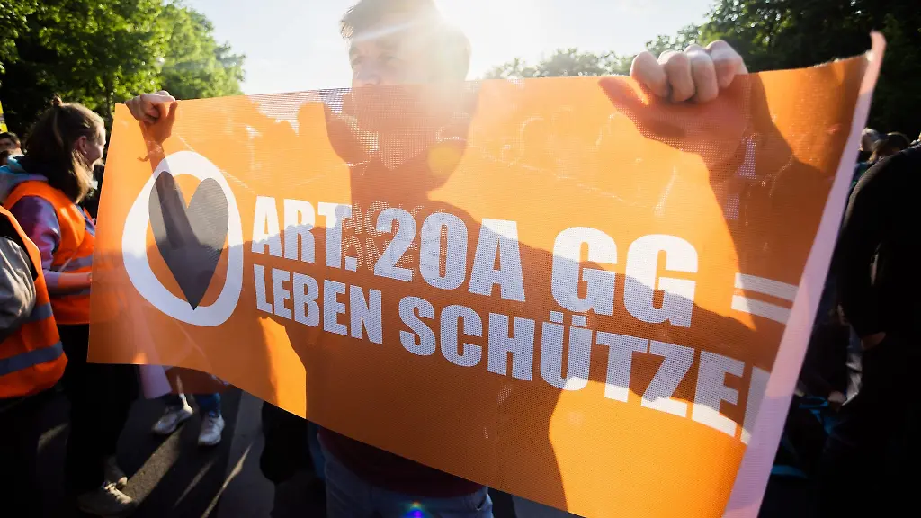 Ein-Teilnehmer-einer-Demonstration-der-Letzten-Generation-haelt-ein-Banner