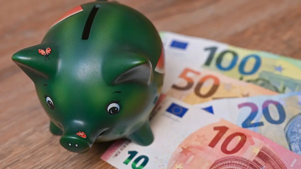 Ein-Sparschwein-steht-auf-einem-Tisch-neben-Eurobanknoten