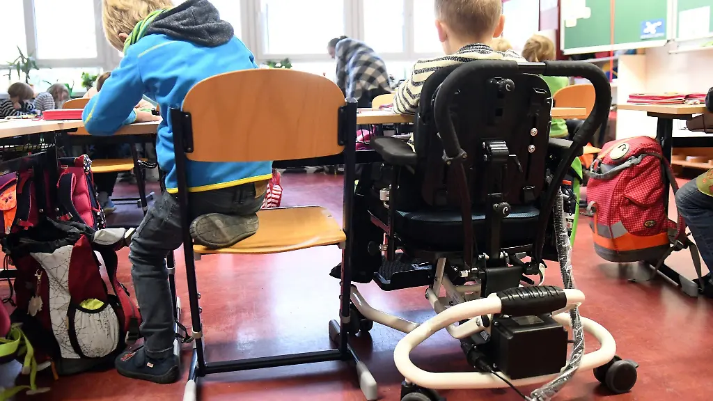 Ein-Kind-sitzt-in-seinem-Rollstuhl-gemeinsam-mit-anderen-Schuelern-in-einem-Klassenraum