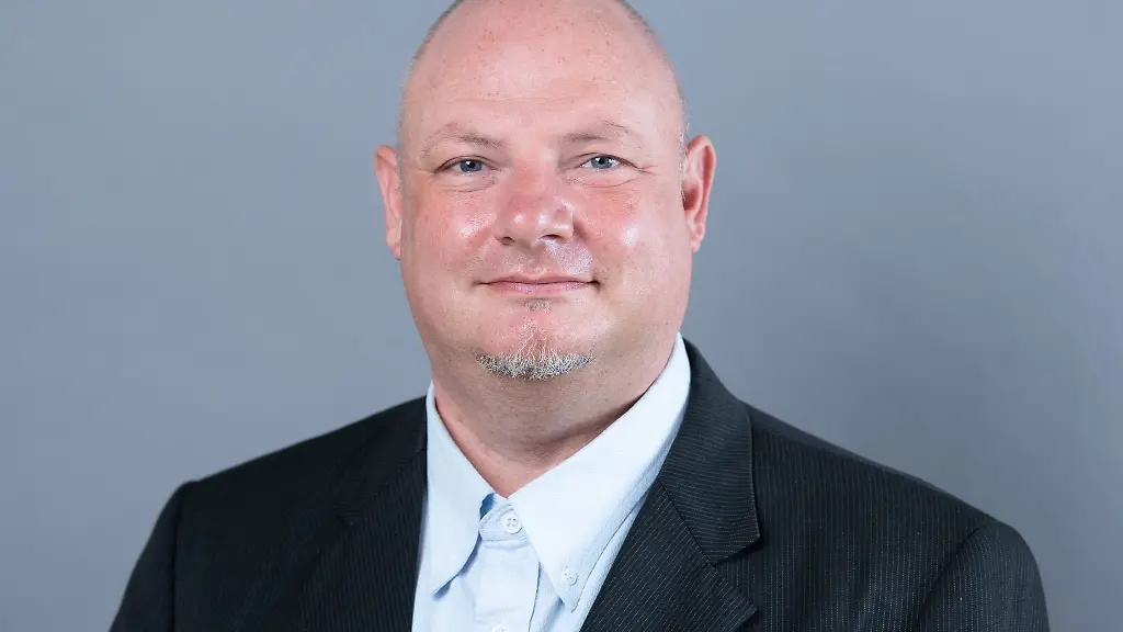 Hendrik-Lange-Die-Linke-klimaschutzpolitischer-Sprecher-seiner-Partei-steht-vor-einer-Fotowand