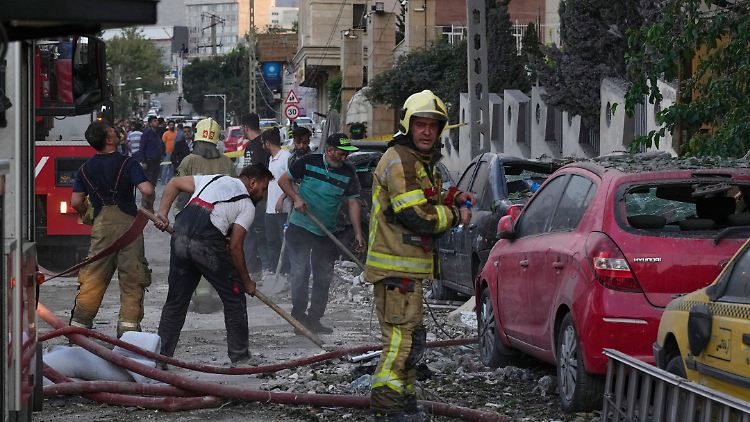 Menschen säubern am Freitag eine Straße in Teheran nach einem israelischen Angriff auf ein Wohngebäude. 