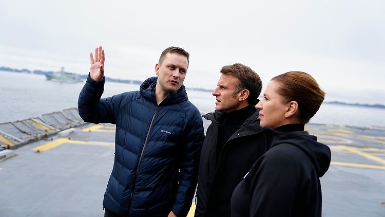 Frankreichs Präsident Emmanuel Macron (M.) in Begleitung der dänischen Ministerpräsidentin Mette Frederiksen und des Premiers von Grönland, Jens-Frederik Nielsen - auf einer dänischen Fregatte in der Hauptstadt Nuuk.