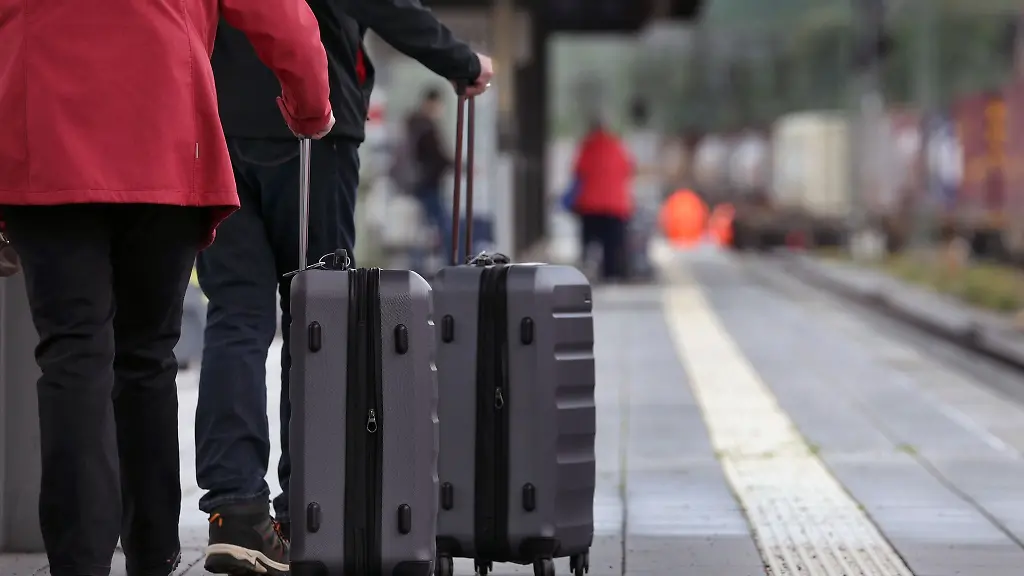 Reisende-mit-Koffern-stehen-im-Hauptbahnhof-an-einem-Bahnsteig