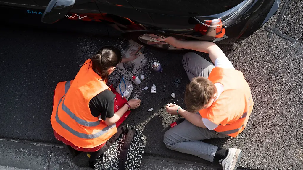 Aktivisten-kleben-sich-bei-einer-Blockade-der-Letzten-Generation-auf-der-Autobahn-100-an-ein-Auto