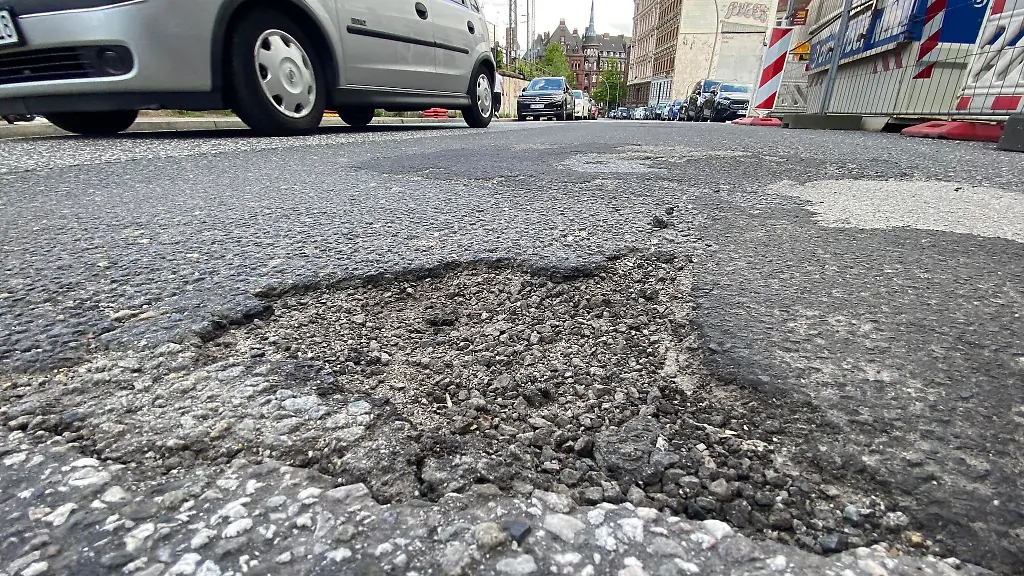 Ein-Schlagloch-ist-auf-einer-Strasse-in-der-Innenstadt-zu-sehen