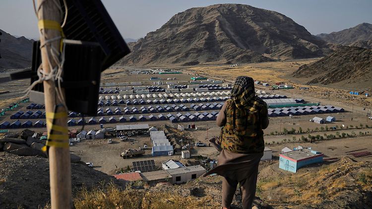 Ein Taliban blickt auf ein Lager, in dem Afghanen untergebracht sind, die aus Pakistan zurückgeführt wurden.