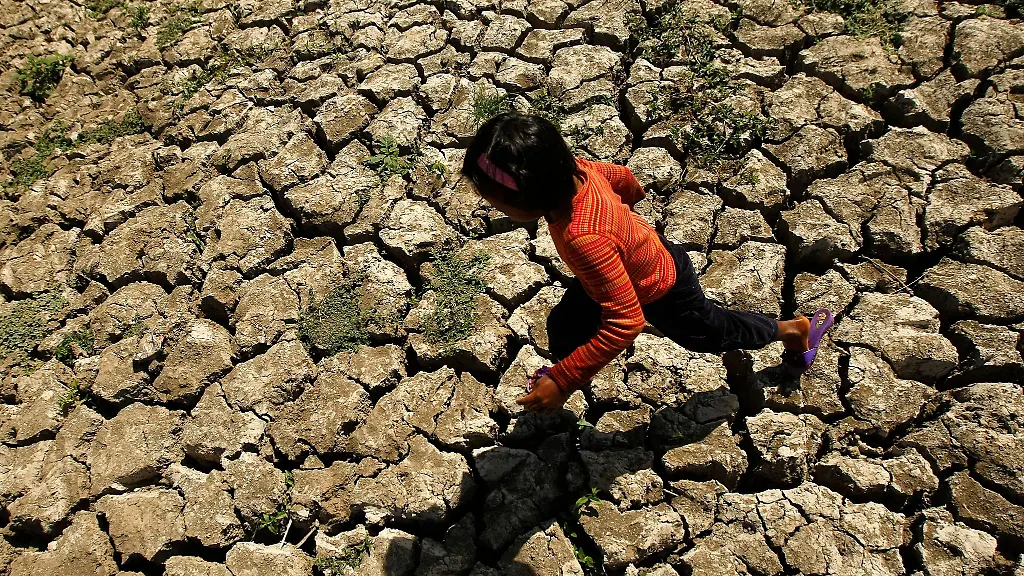 Ein-philippinisches-Kind-laeuft-in-der-Provinz-Cavite-auf-den-Philippinen-in-einem-ausgetrockneten-Bewaesserungskanal-der-durch-das-Wetterphaenomen-El-Nino-ausgetrocknet-war