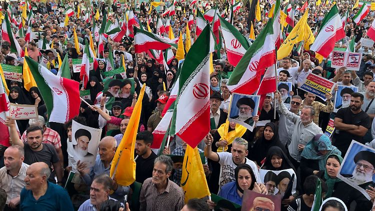 Bei der Feier werden iranische Nationalflaggen und Banner mit Parolen geschwenkt.