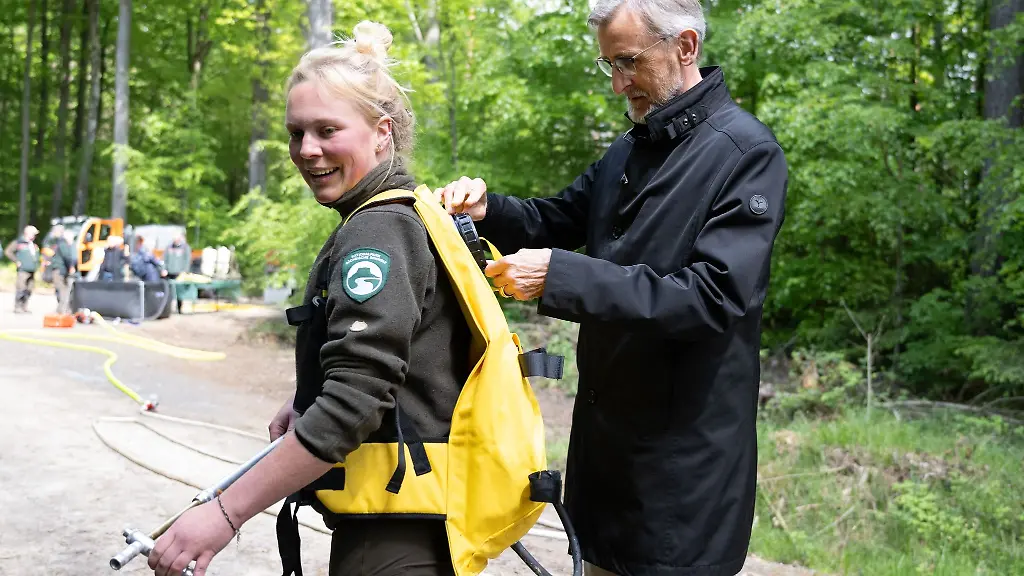 Innenminister-Armin-Schuster-inspiziert-den-Loeschrucksack-von-Natalie-Richter-Nationalparkwaechterin