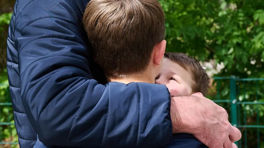 Ein-Vater-umarmt-seine-beiden-Soehne