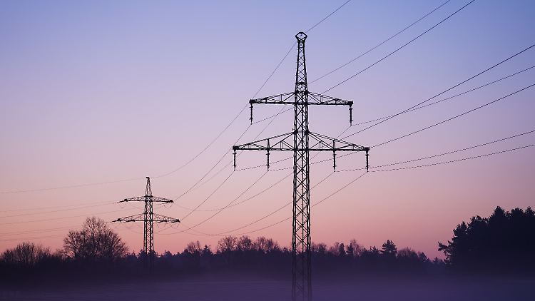 Nebel zieht über ein Solarfeld mit darüber laufender Stromleitungen.