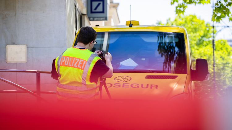 Ein Polizist fotografiert nach dem Überfall den Geldtransporter vor einer Bankfiliale am Kurfürstendamm. 