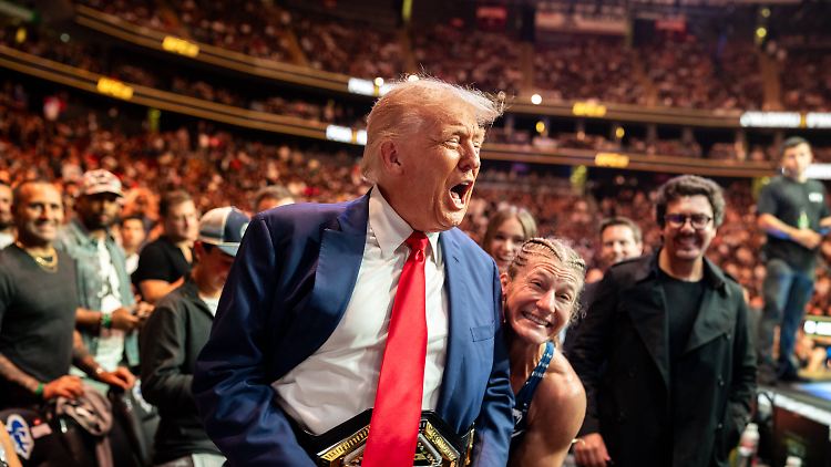 Trump bekommt von UFC-Kämpferin Kayla Harrison den Championgürtel umgeschnallt.
