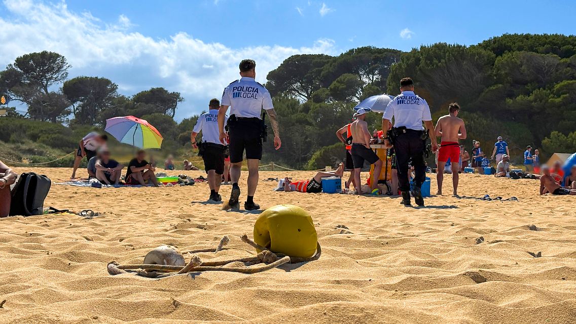 Polizisten der Policia Local laufen Streife am Strand Cala Agulla und suchen nach verbotenen fliegenden Händlern und Glasflaschen mit alkoholischen Getränken.