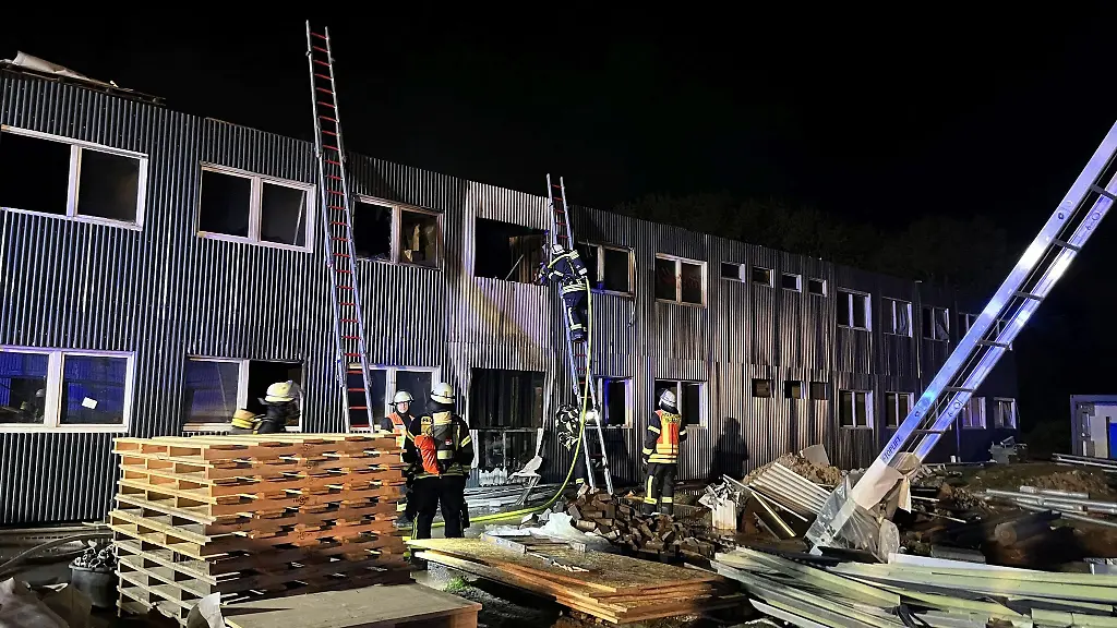 Feuerwehrleute-loeschen-einen-Brand-in-einer-fuer-Gefluechtete-vorgesehenen-Containeranlage