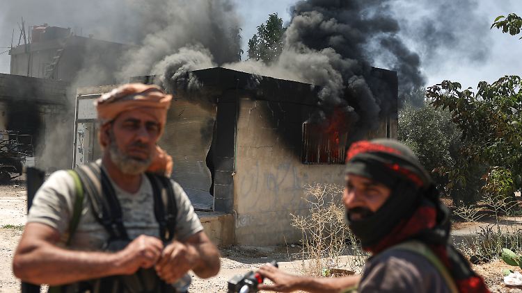 Beduinische Kämpfer vor einem niedergebrannten Geschäft im Dorf Al-Masraa am Rande der Stadt Suwaida. 