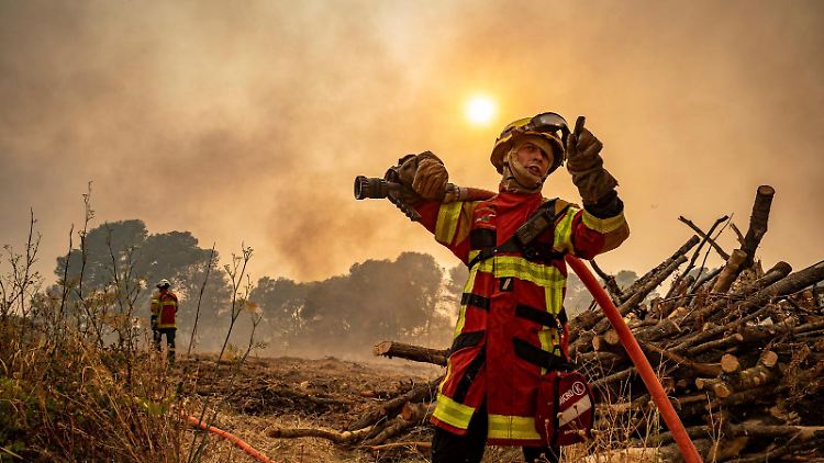 Ein Feuerwehrmann, der in der Nähe von Saint-Laurent-de-la-Cabrerisse, Südfrankreich, mit einem Schlauch gegen einen Waldbrand vorgeht.