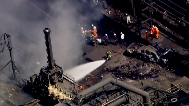 Feuerwehrleute kämpfen vor dem zerstörten Industriegebäude gegen die Flammen. Mittlerweile ist der Brand gelöscht.