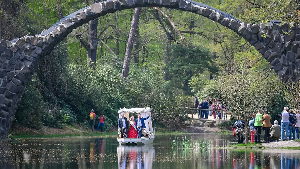 Die-frisch-getaufte-Hochzeitskahn-Emilie-faehrt-unter-der-Rakotzbruecke-im-Rhododendronpark-Kromlau-durch