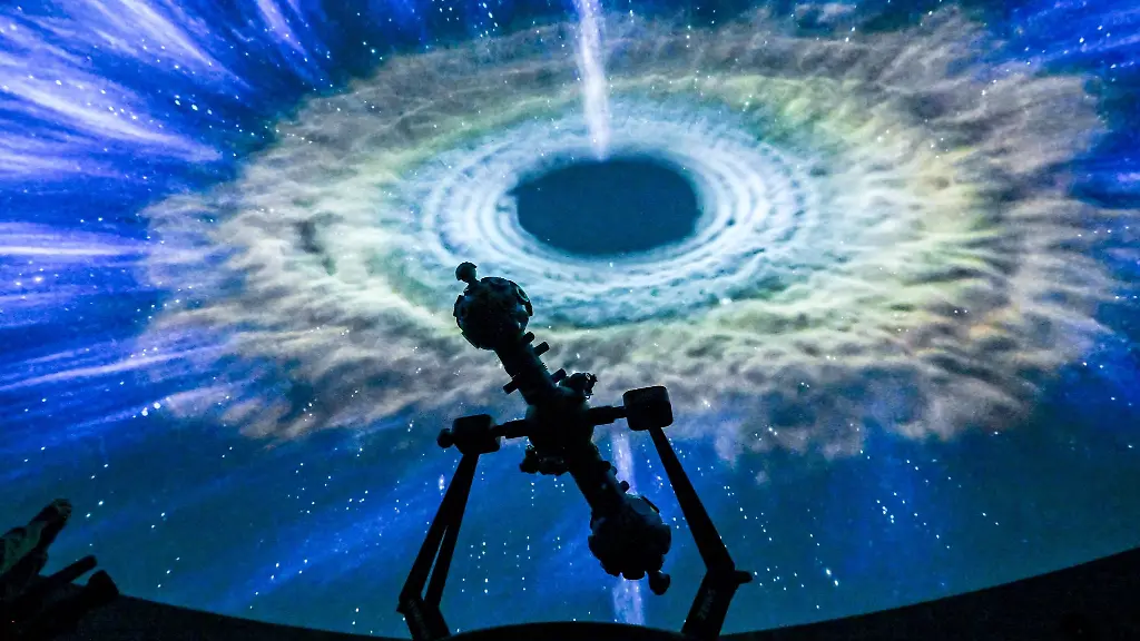 Die-Projektion-einer-Galaxie-ist-im-Sternensaal-des-Planetariums-hinter-dem-Projektor-zu-sehen