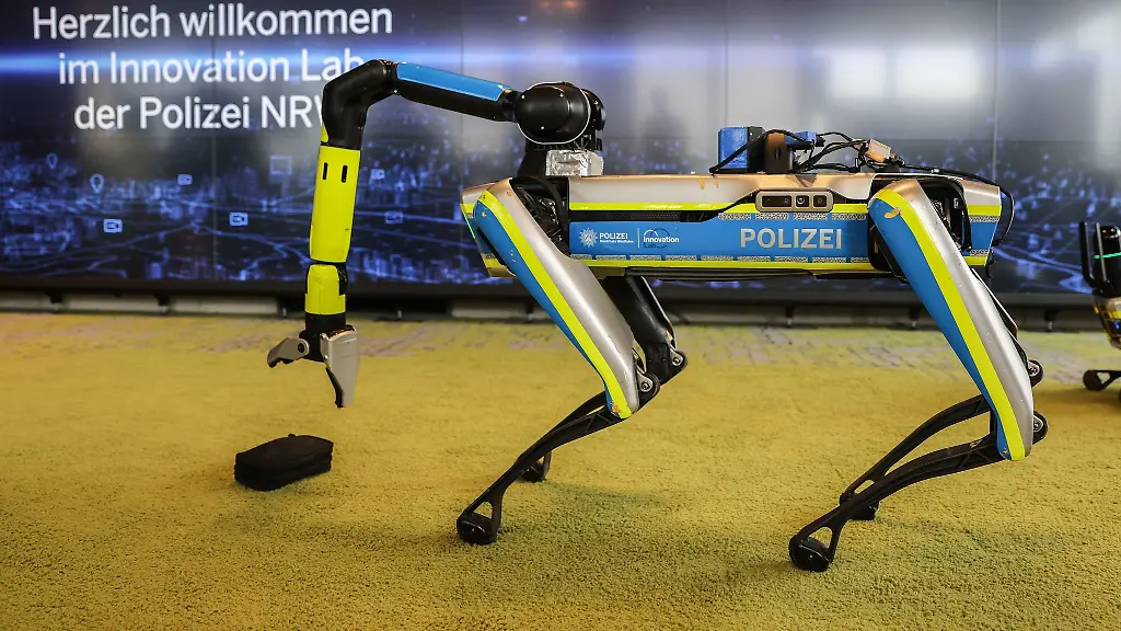 Ein-Polizeiroboter-hebt-in-einer-Trainingssituation-eine-Tasche-auf
