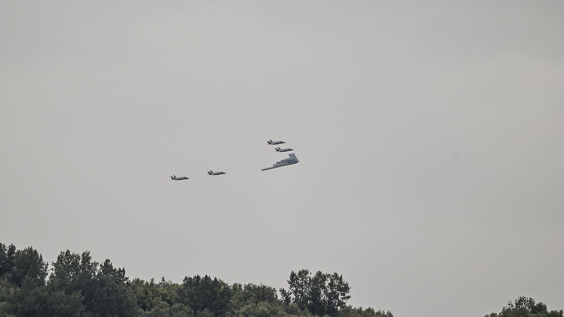 ... Ein B2-Tarnkappenbomber und vier F-35-Kampfjets donnern anscheinend unangekündigt über die Köpfe der Staatschefs hinweg.