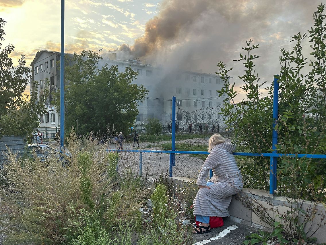 Eine Bewohnerin betrachtet ein brennendes Wohnhaus in Charkiw. Das Feuer soll laut ukrainischen Behörden durch einen russischen Angriff ausgelöst worden sein.