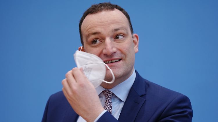 Jens Spahn nimmt zu Beginn der Pressekonferenz zur Entwicklung in der Corona-Pandemie in der Bundespressekonferenz die FFP2-Maske ab.