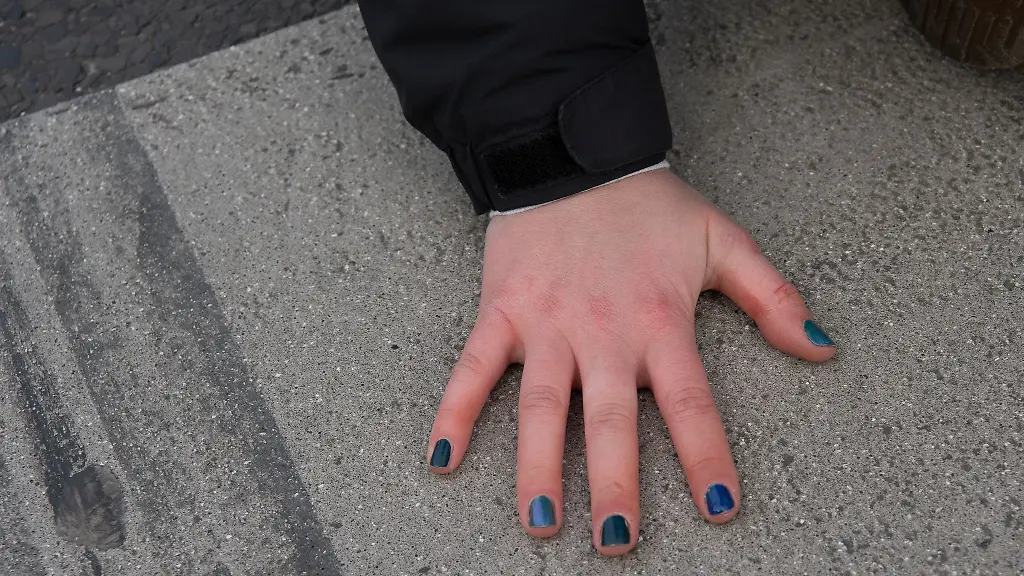 Mit-bunten-Fingernaegeln-sitzt-eine-Aktivistin-bei-einer-Blockade-der-Gruppierung-Letzte-Generation