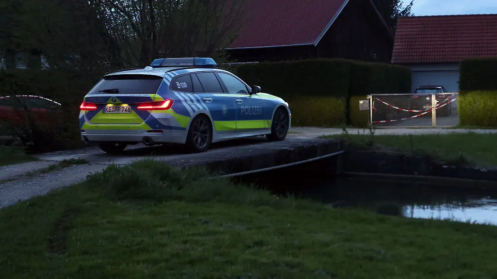 Ein-Polizeiauto-steht-am-Abend-vor-einem-Einfamilienhaus