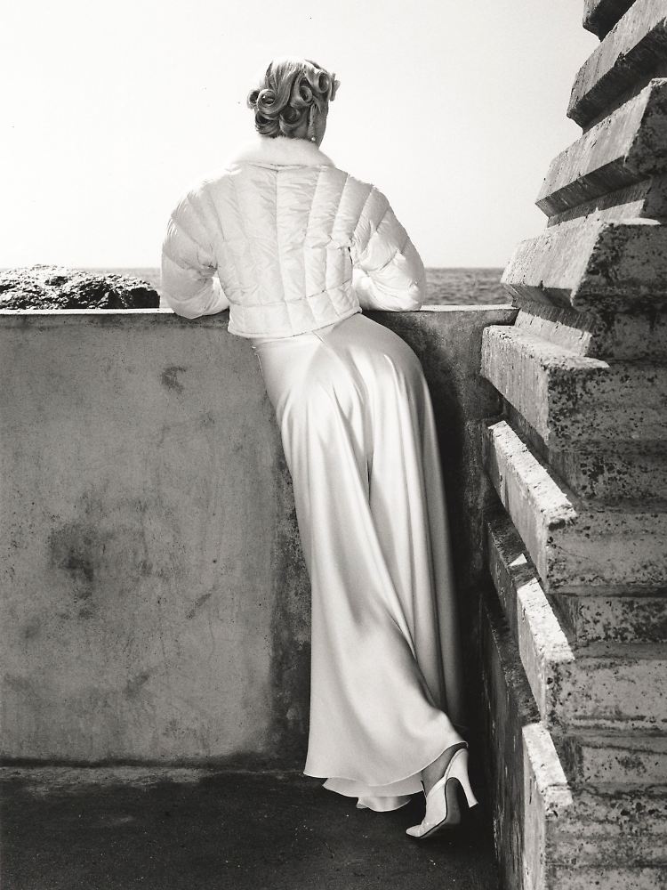 Frau, die über eine Brüstung schaut. Ebenfalls fragen wir uns: Wohin? (Eva Herzigova, Blumarine, Monaco 1995)