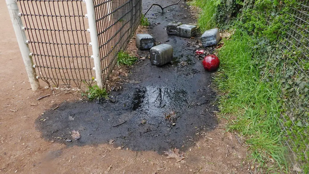 Mehrere-Kanister-liegen-in-einer-Pfuetze-aus-Altoel-hinter-einem-Fussballtor