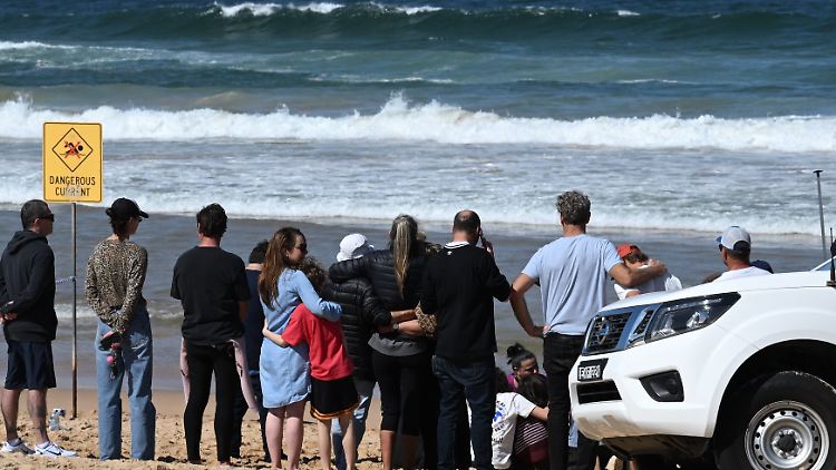 Familienangehörige und Freunde trauern am Long Reef Beach. 