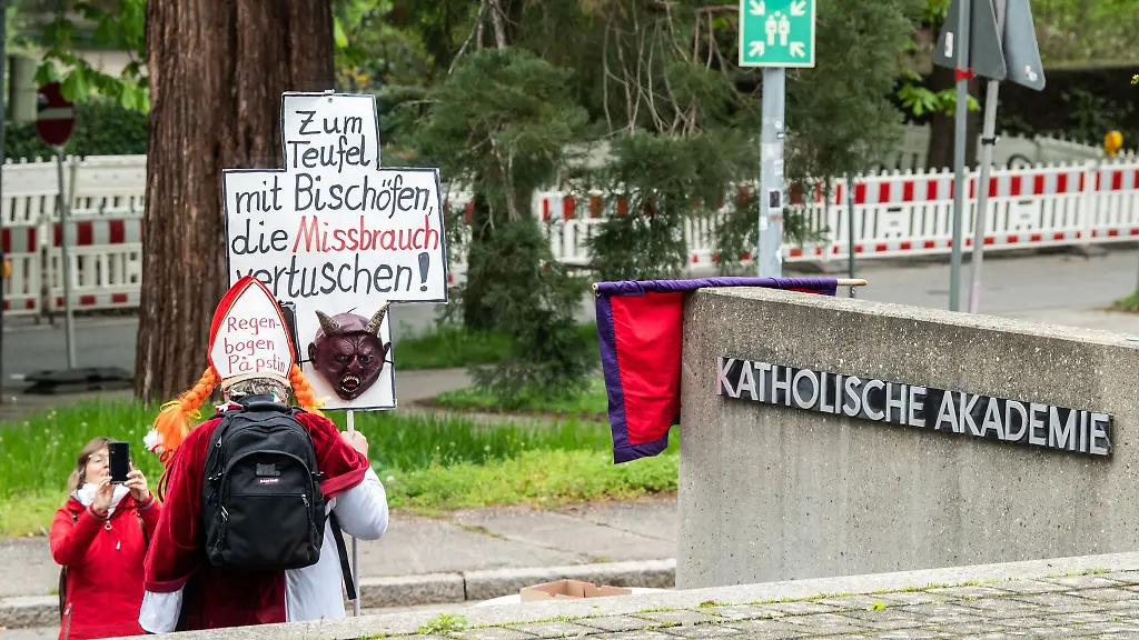 Ein-Mann-haelt-vor-der-Katholischen-Akademie-ein-Schild-mit-der-Aufschrift-Zum-Teufel-mit-Bischoefen-die-Missbrauch-vertuschen