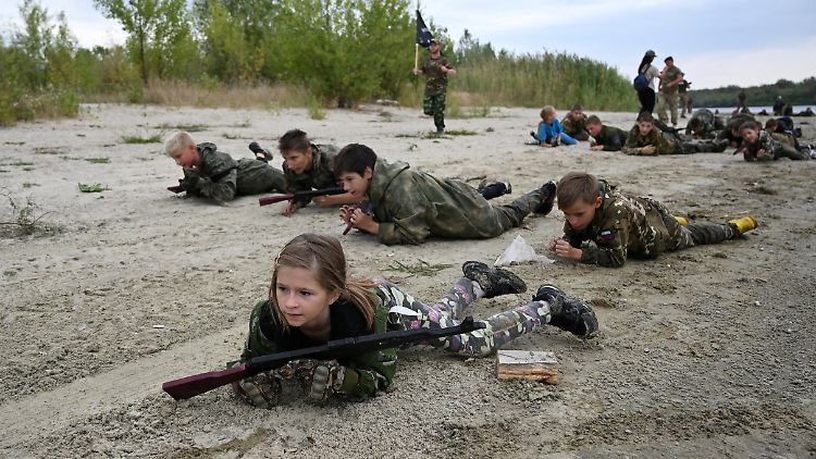 Kinder robben in einem russischen Militärcamp bei Rostow durch den Sand.