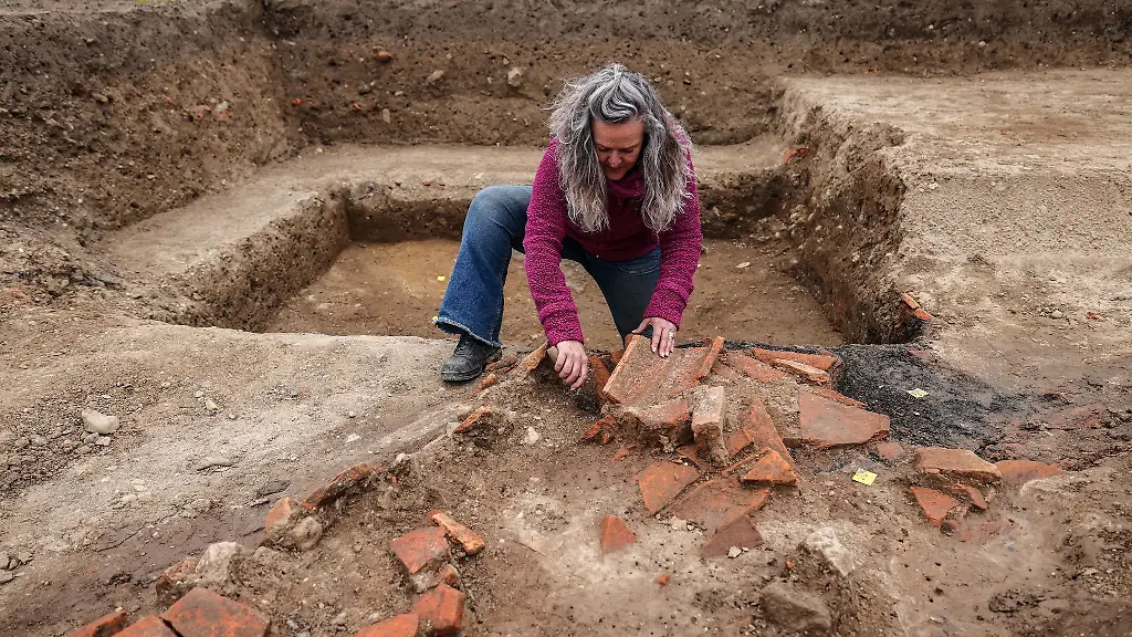 Ein-Archaeologin-legt-im-Xantener-Ortsteil-Birten-Dachziegel-eines-eingestuerzten-roemischen-Gebaeudes-auf-dem-Gebiet-des-Legionslagers-Vetera-Castra-frei