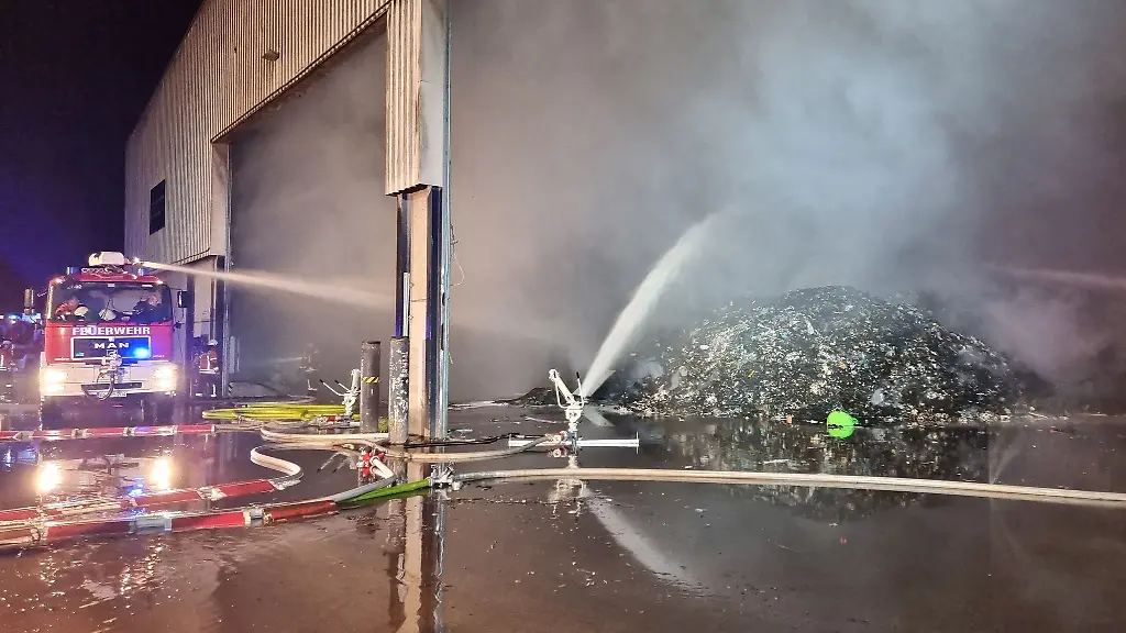 Feuerwehrleute-loeschen-die-Reste-eines-Feuers-in-einer-Halle